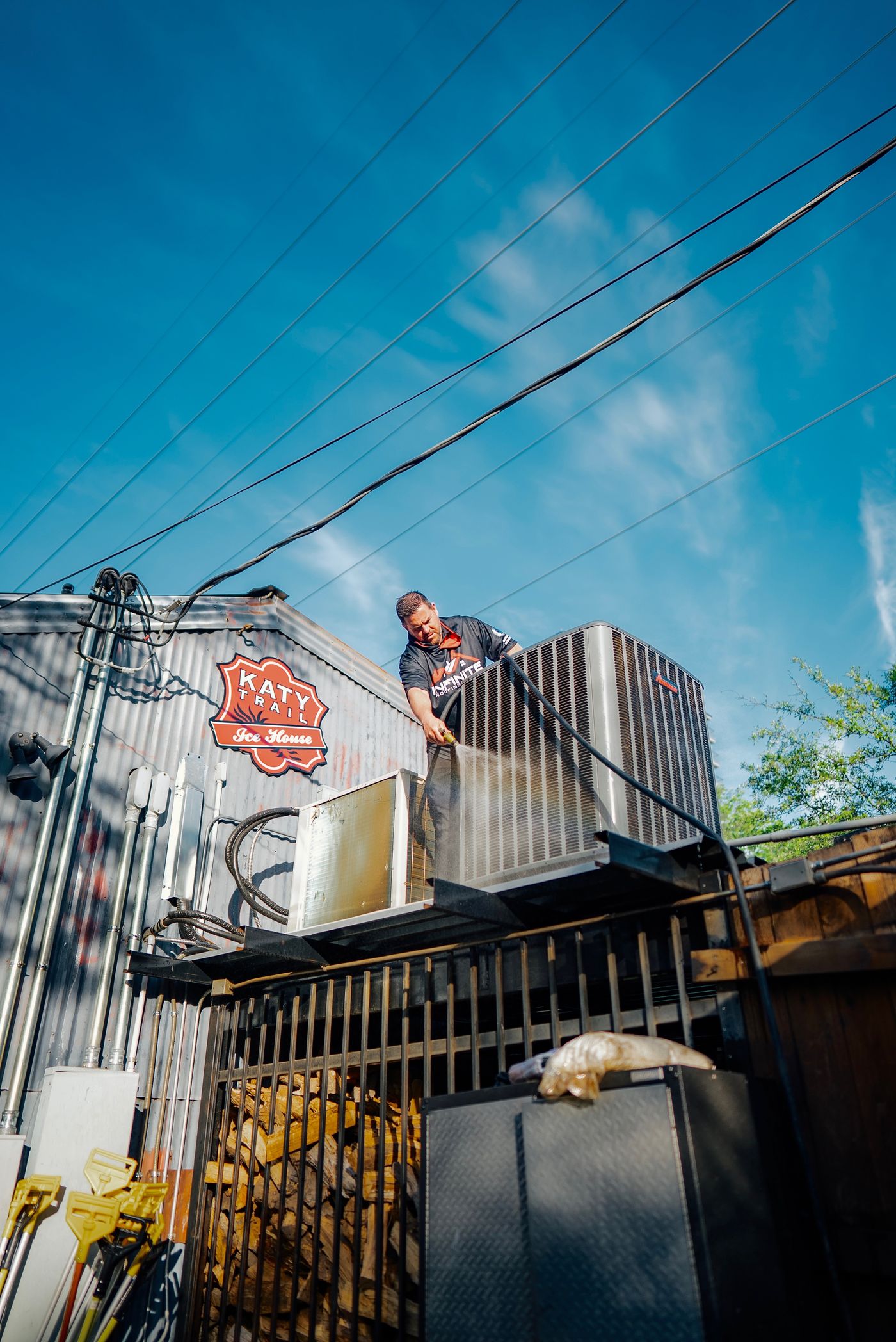 Infinite Home Services technician performing maintenance on commercial condensers at Katy Trail Ice House