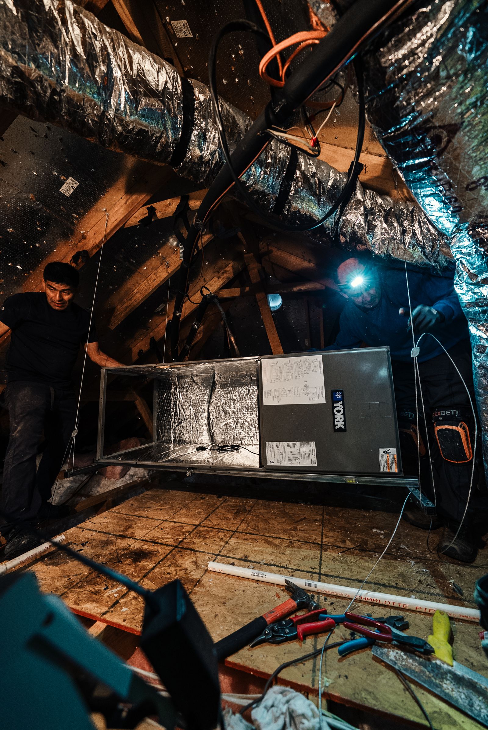Two Infinite Home Services technicians installing a new York system in a North Texas attic