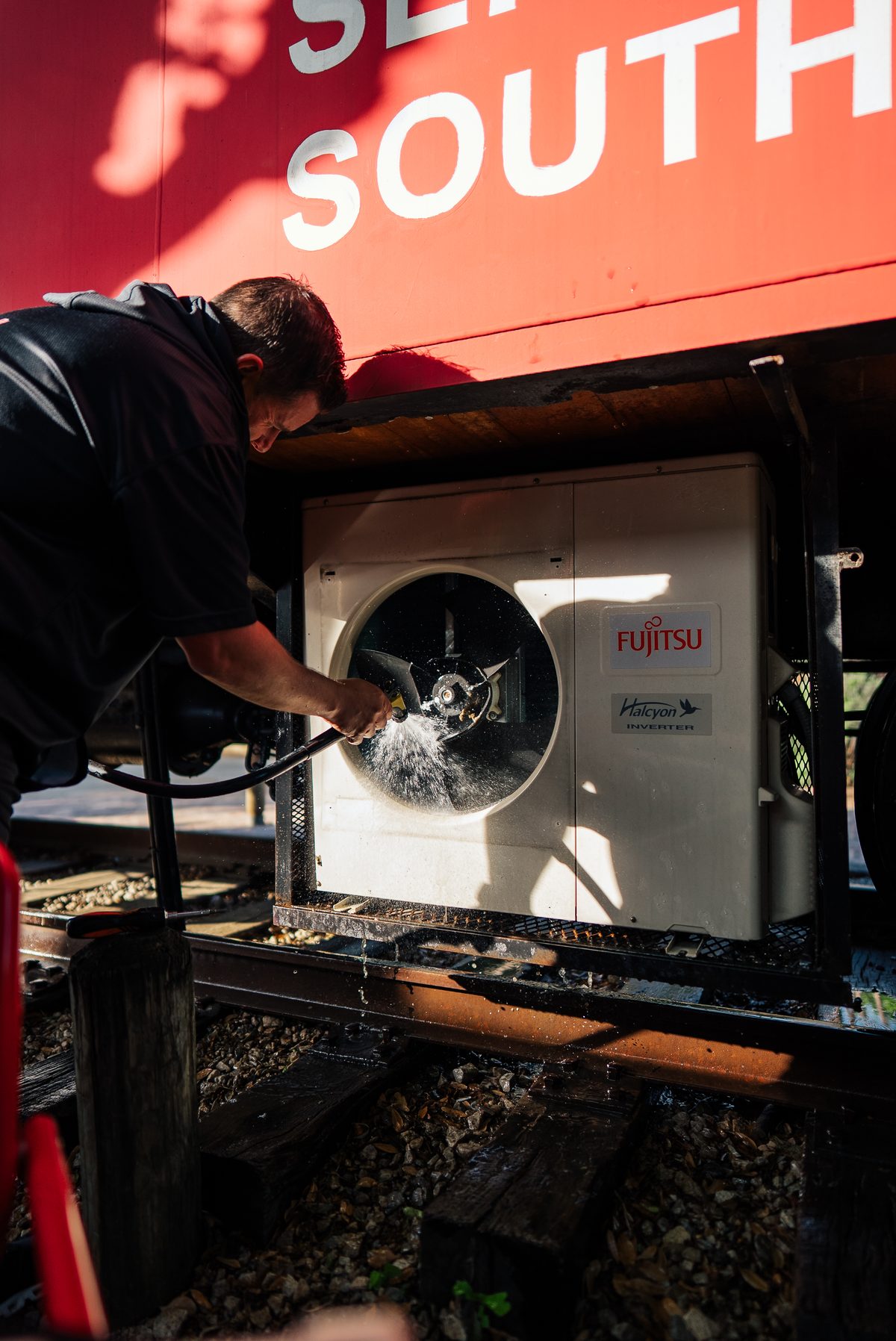 Technician cleaning a Fujitsu mini-split condenser coil