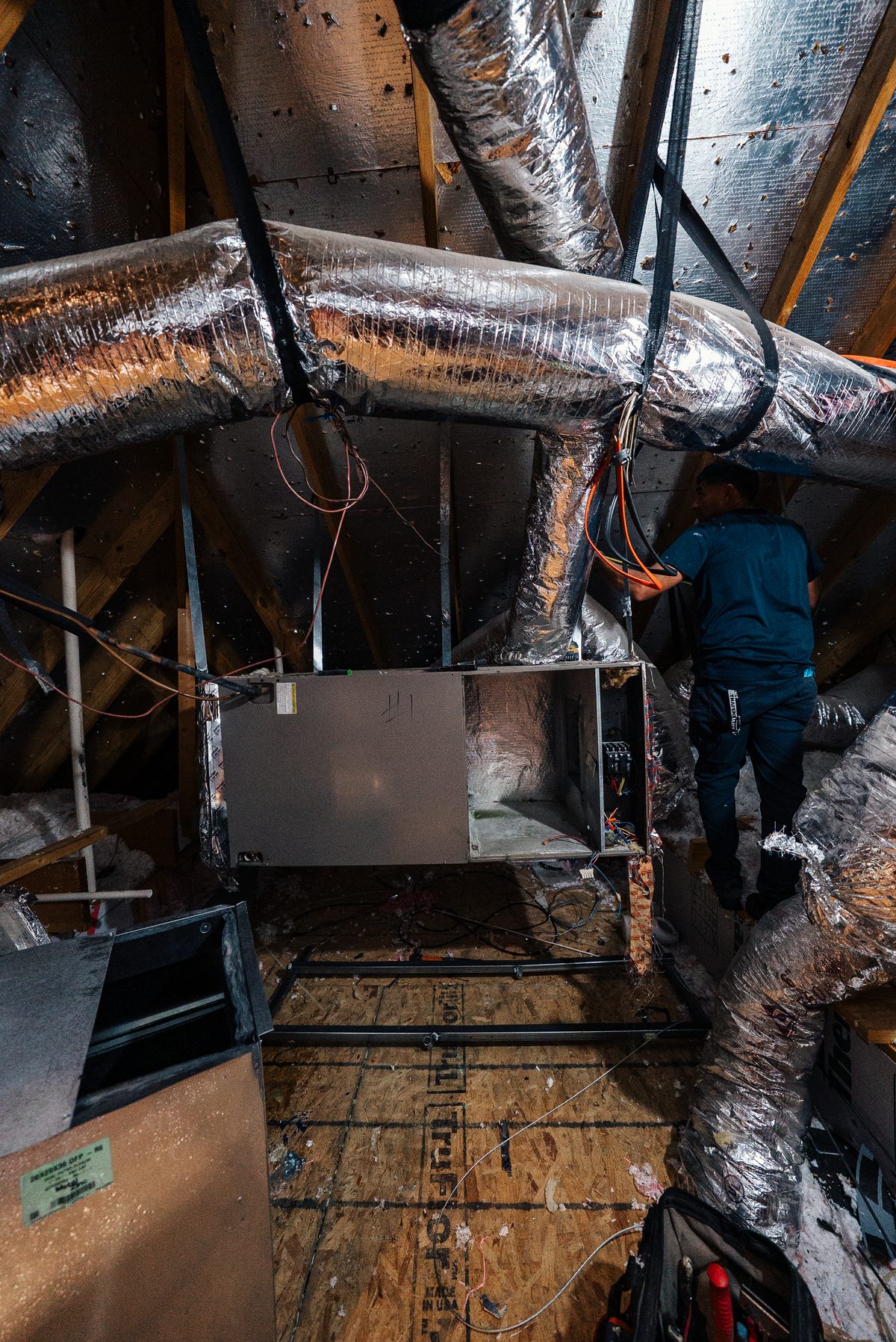 Infinite Home Services technician repairing attic ductwork on a heating system